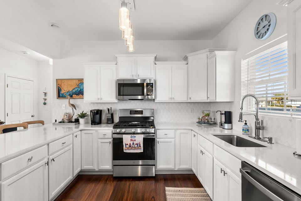 Cook memorable meals in this bright, fully-equipped kitchen with modern appliances, quartz countertops, and stylish pendant lighting.