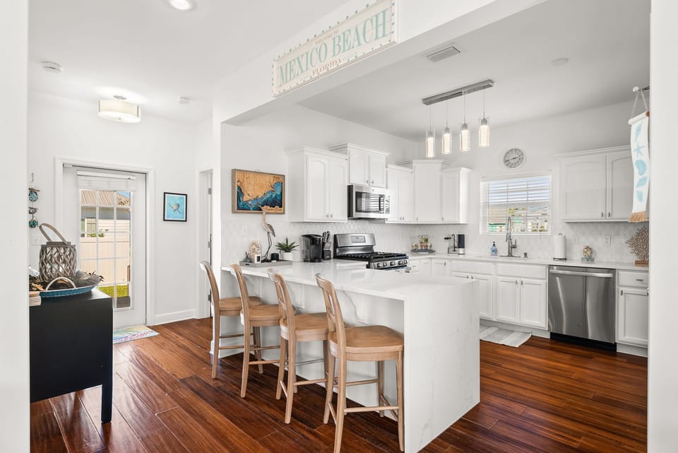 Cook together in this bright, fully-equipped kitchen featuring a large island, modern appliances, and charming coastal touches throughout.