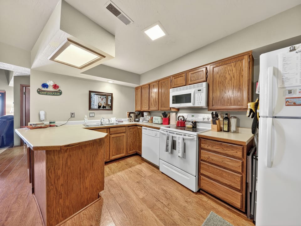 Your fully equipped kitchen awaits with warm wood cabinets and modern appliances, perfect for preparing morning coffee or cooking meals together during your stay.