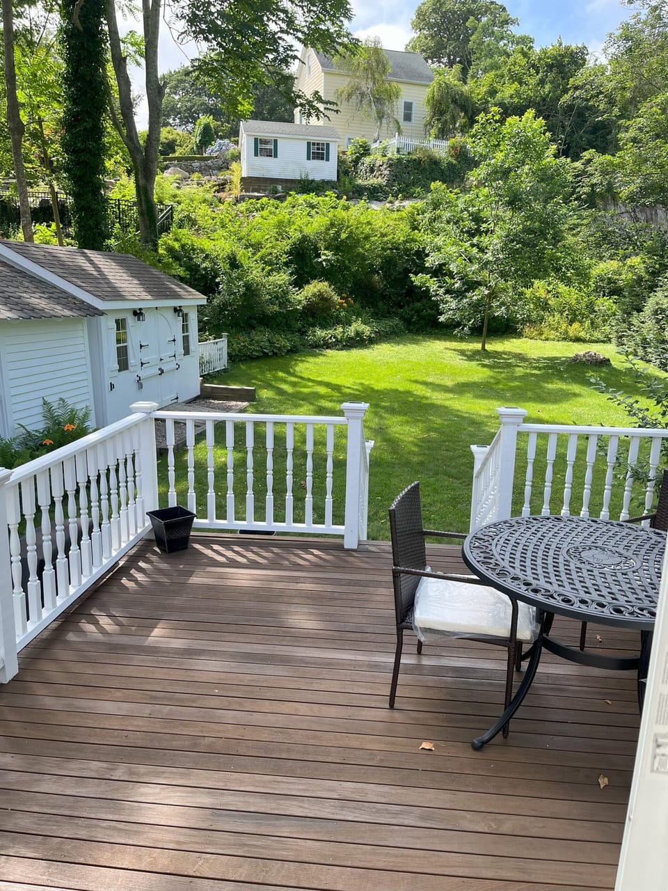 The house has an expansive backyard with greenery and mature plantings 