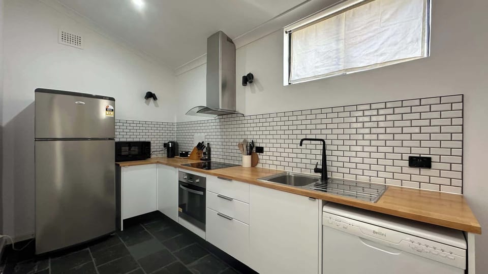 Modern kitchen with stainless steel fridge, tiled splashback, cooktop, oven, and ample cabinetry.