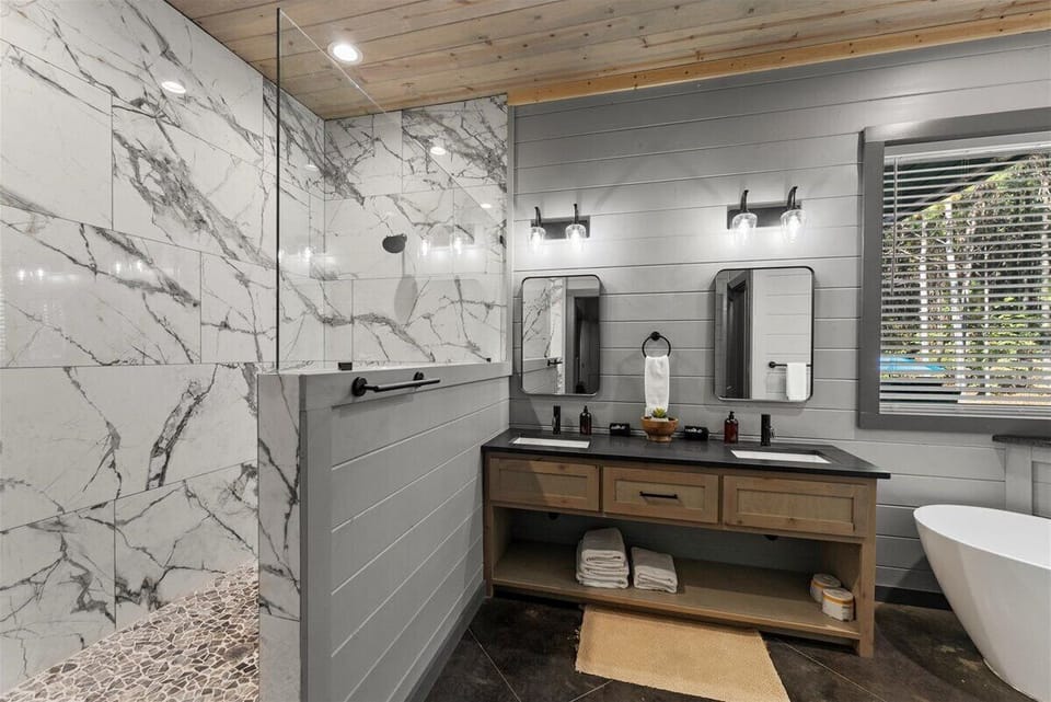 Luxury Master ensuite bathroom with double vanity and marble style walls and deep soaking tub