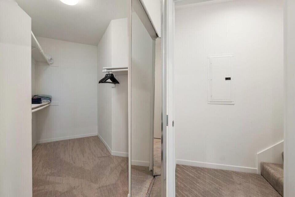Spacious room with plush carpet and a large, well-organized closet.