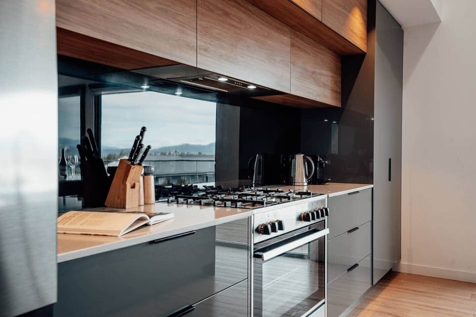 Modern kitchen equipped with a cooktop, oven, dishwasher, coffee machine, and kettle for your convenience.