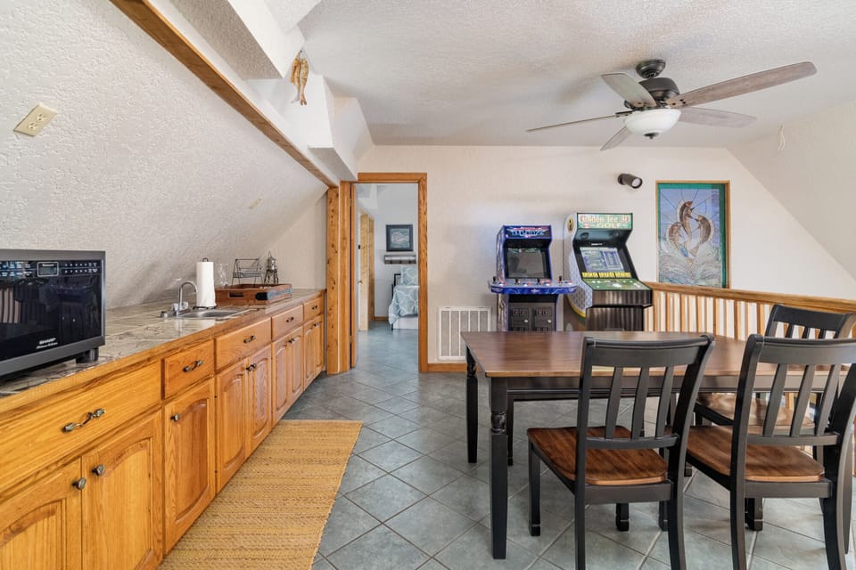 Upstairs kitchenette and game area complete with classic arcade machines—ideal for teens, kids, or an extra private family space.