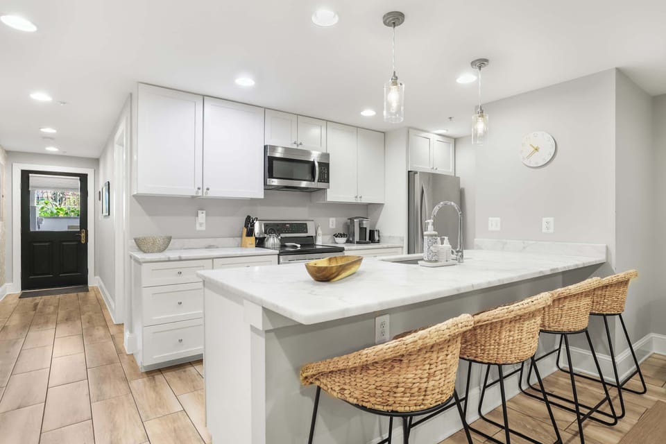 View of main door and fully equipped kitchen with counter and bar stools