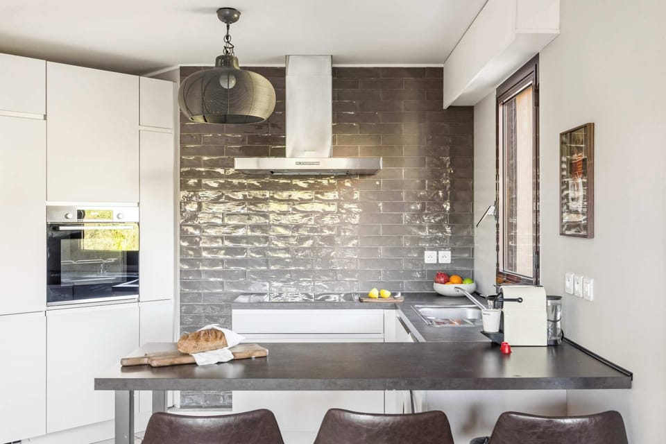 Striking kitchen with glossy backsplash and bar seating — designed for quick breakfasts or wine nights in.