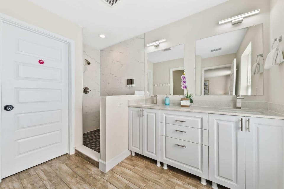 Ensuite bathroom with walk-in shower, dual sinks, toilet, and hair dryer.