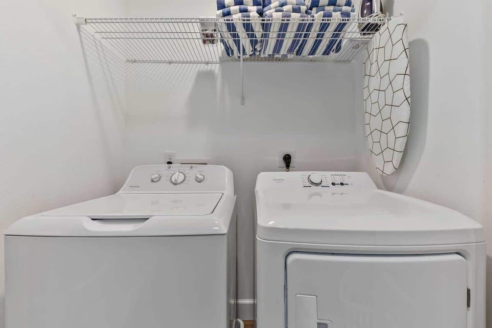 A closer look at the in-unit laundry area, featuring a washer and dryer with an overhead storage shelf for towels and essentials, providing added convenience for guests.