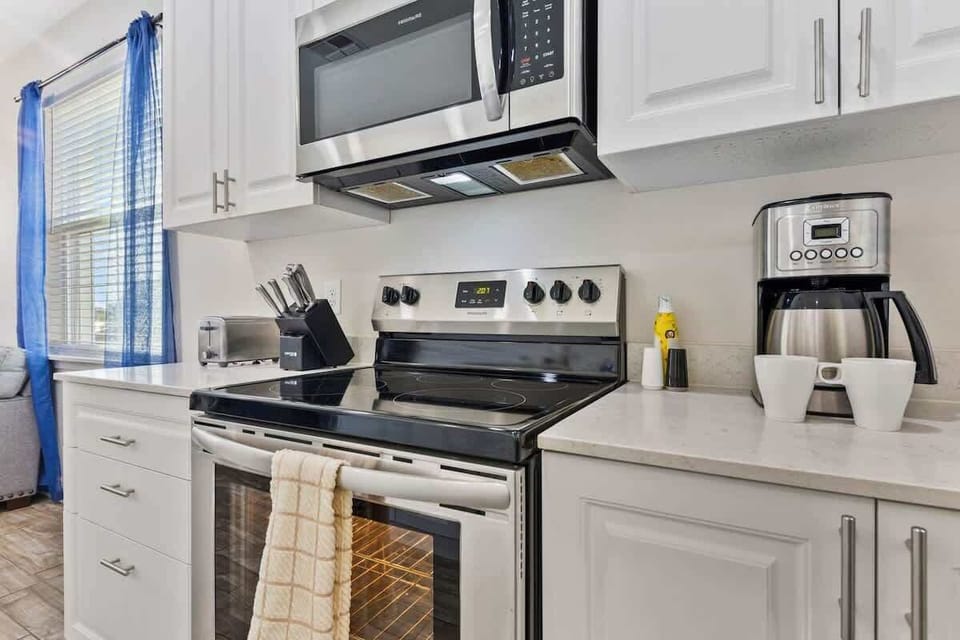 Kitchen with stove, oven, microwave, dishwasher, refrigerator, coffee maker, and hot water kettle.