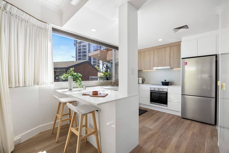 The sleek kitchen blends form and function with stone benchtops, quality appliances, and a Nespresso machine—perfect for brewing morning coffee before a day by the sea.