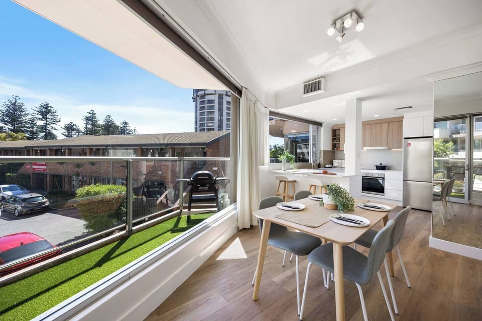 Gather for relaxed meals in the light-filled dining area, where natural light, elegant furnishings, and leafy views create an inviting setting for conversation and connection.