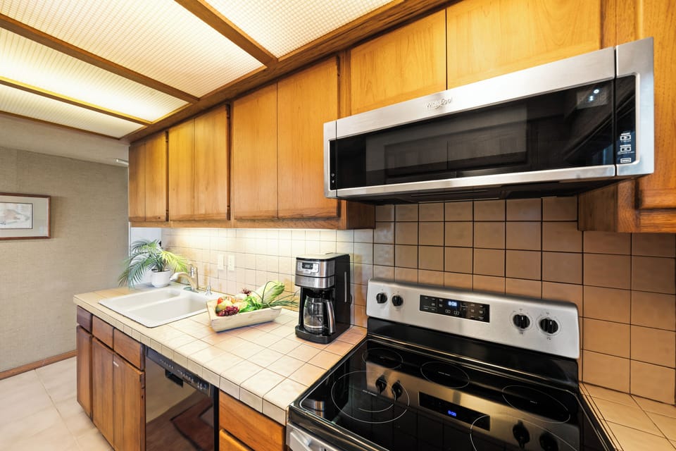 Clean, well‑equipped cooking area featuring a full stove, microwave, and coffee station