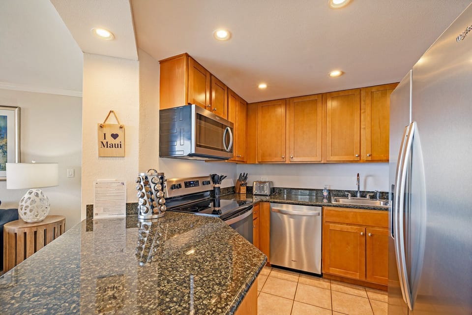 Full view of the kitchen featuring warm cabinetry, granite countertops, and a full set of modern appliances, including a large refrigerator.