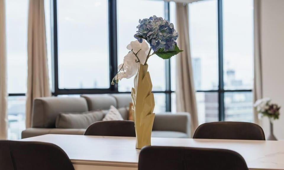 A chic and modern dining area featuring a long wooden table decorated with a vibrant floral arrangement
