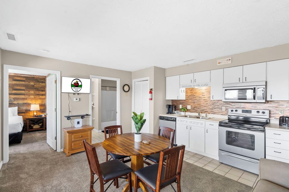 The open floor plan features a fully equipped kitchen, a dining table, a living area with a sleeper sofa and patio access, a bedroom, and a bathroom.
