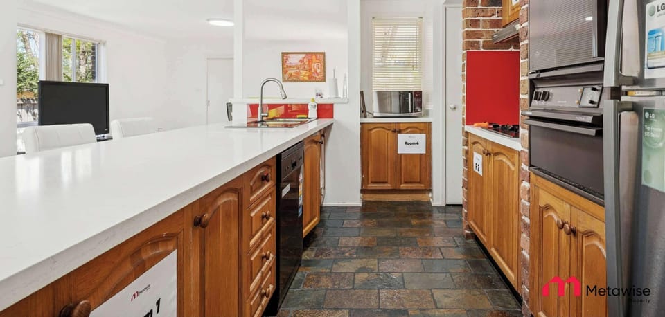 Shared kitchen with long white countertop, wooden cabinetry, and modern appliances