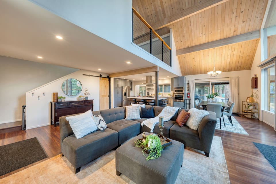 Spacious open-concept great room featuring vaulted wood ceilings, a cozy sectional, and seamless flow into the chef’s kitchen and dining area.