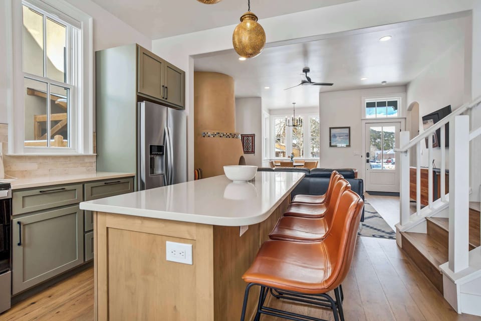 Stainless appliances, warm wood cabinetry, and bar-style seating make this kitchen both functional and welcoming. Natural light and open shelving add a relaxed, modern touch.