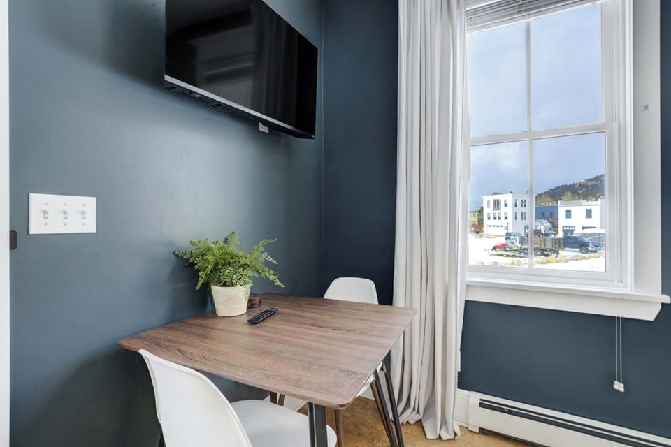 A compact dining table sits beside a window with neighborhood views, paired with a wall-mounted Smart TV for added convenience. It’s a perfect spot for quick meals or morning coffee.