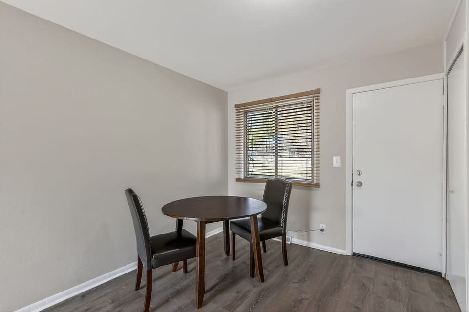Cozy dining nook with a round table for two, perfect for morning coffee or intimate meals. Natural light from the window, modern flooring, and a clean, minimalist vibe make it both functional and welcoming.