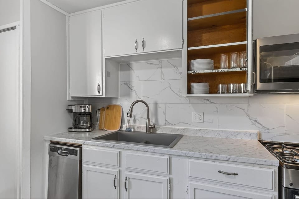 Bright, fully equipped kitchen with stainless steel appliances, quartz-style counters, and crisp white cabinetry. Includes dishwasher, microwave, coffee maker, and full-size fridge…perfect for cooking at home or quick meals on the go.