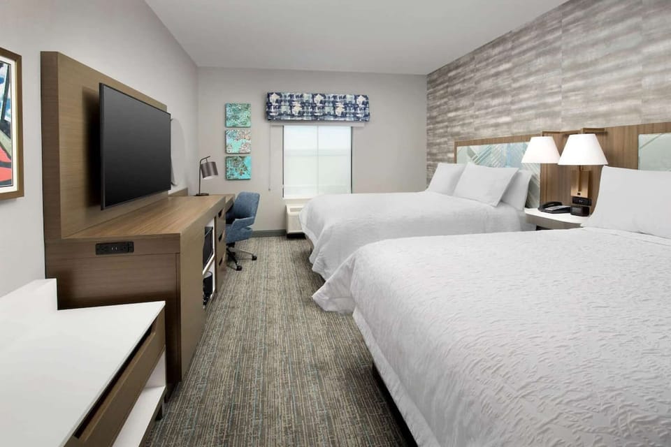 Double-bed room with desk, large TV, and cozy lighting by the window