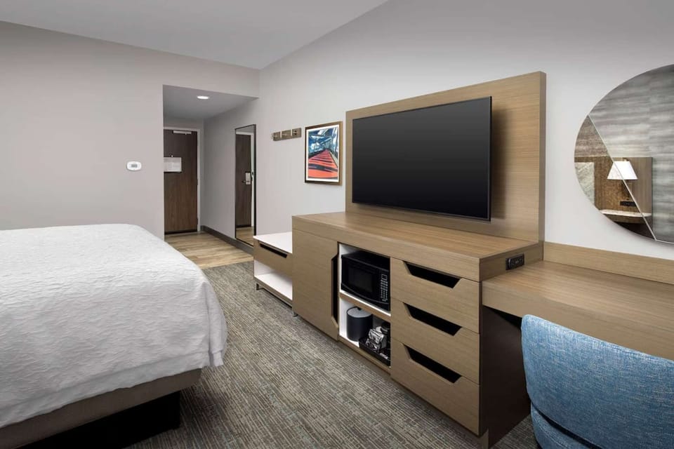 Flat-screen TV, desk, and storage space beside the bed