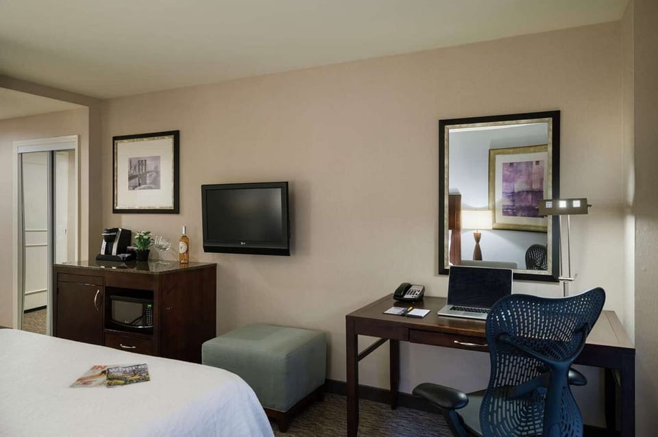 Desk, TV, and coffee area beside a king bed in a bright room