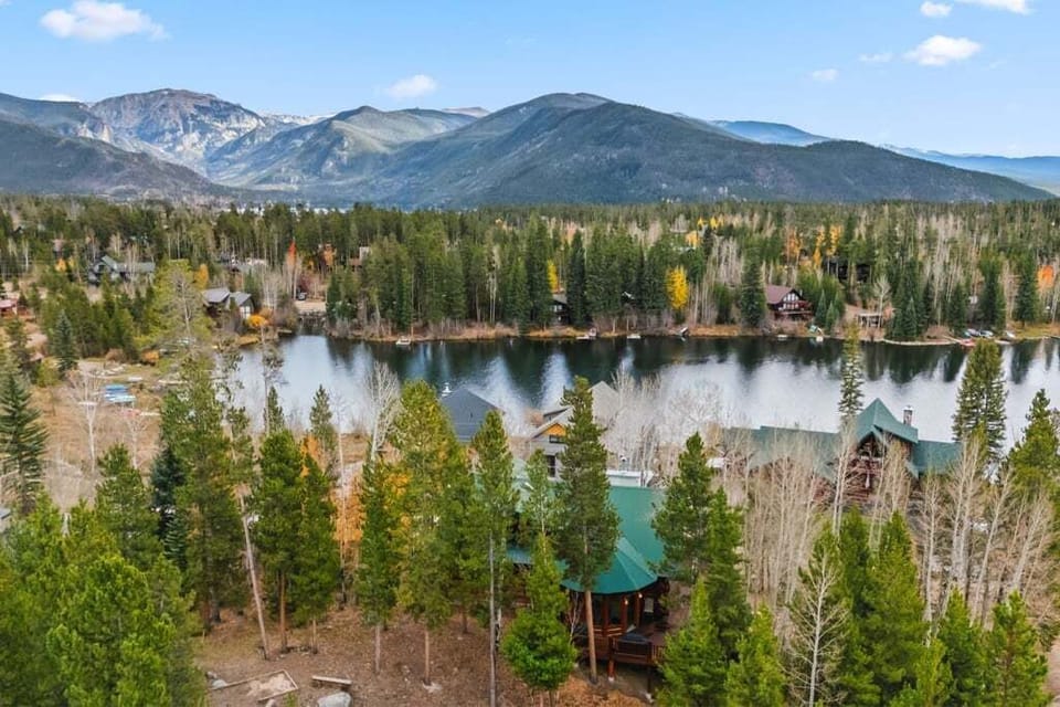 Stunning mountain lakeside property nestled among autumn aspens and evergreens with dramatic Rocky Mountain backdrop.