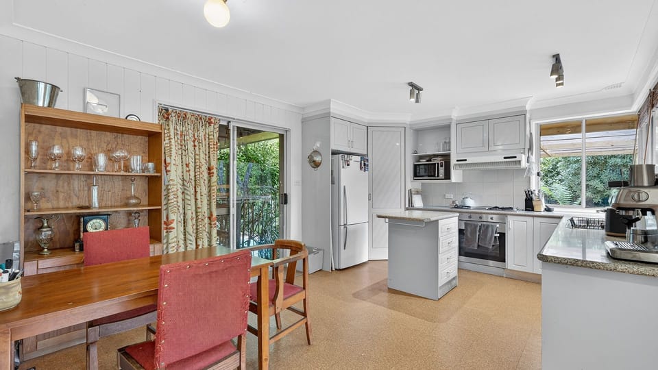 Warm dining area with timber cabinetry and leafy outlook.