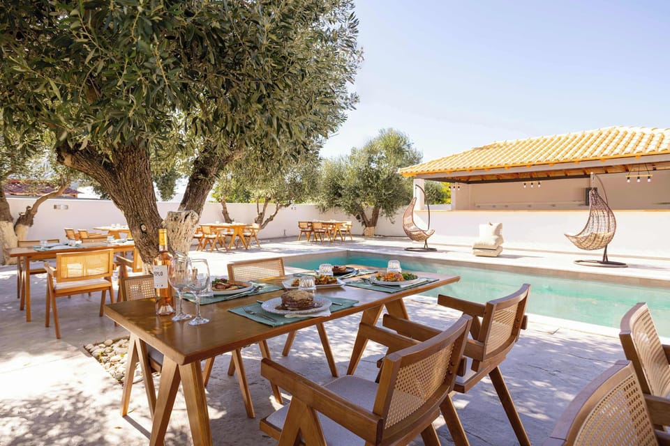 Shared Pool Area Framed by Olive Trees and Wooden Dining Tables
Beautiful communal pool surrounded by natural stone, mature olive trees, and rustic dining spaces perfect for outdoor meals in the shade.