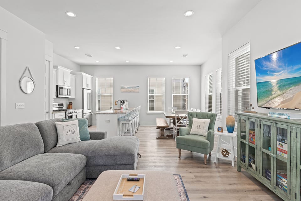 Unwind in your bright, coastal-inspired living space where soft gray sofas and sea-green accents create perfect harmony for relaxation and connection.