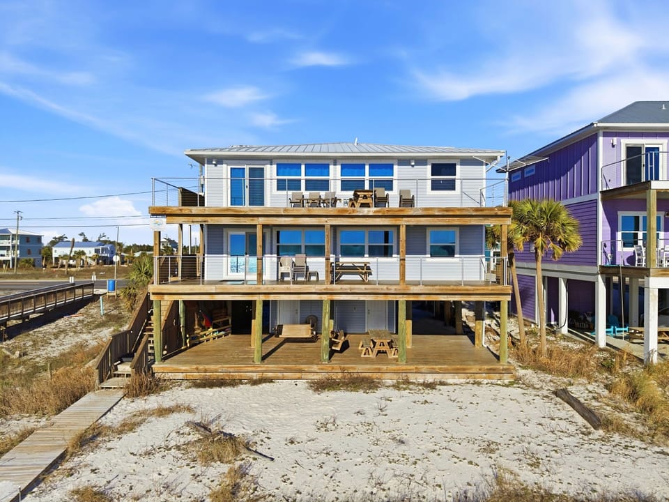 This coastal property sits directly on the sandy shore with multiple deck levels overlooking the beach. A private pathway leads from the sand to your own waterfront retreat, perfect for sunsets and relaxation.