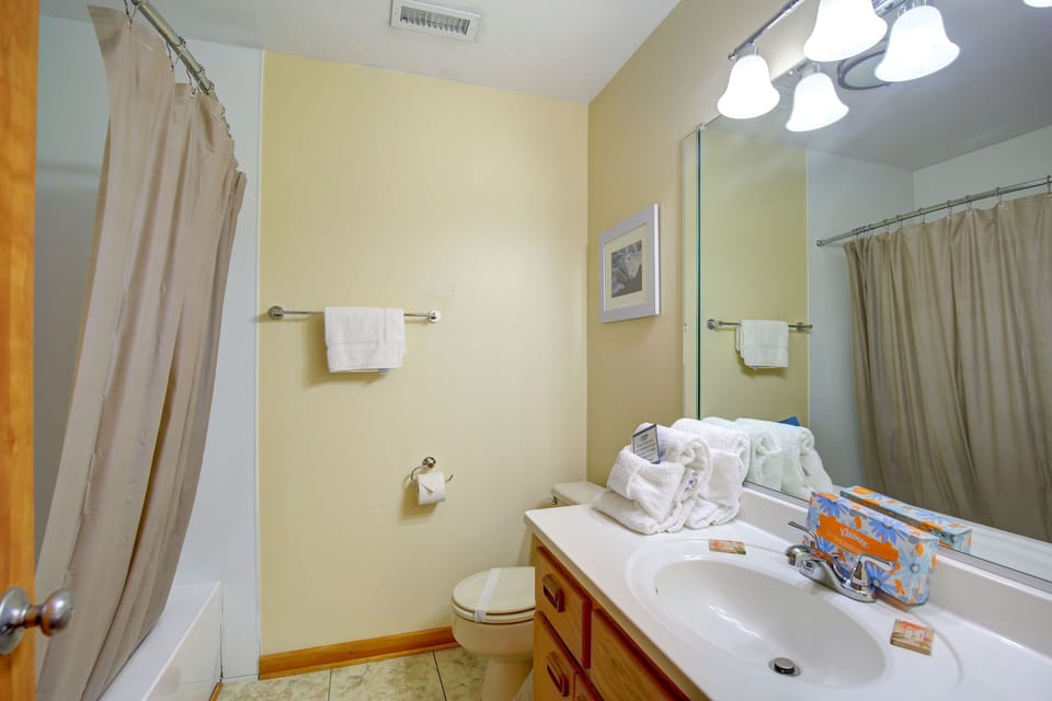 The well-appointed bathroom offers a clean and cozy atmosphere, complete with fresh towels, a shower, and essential toiletries for your convenience.
