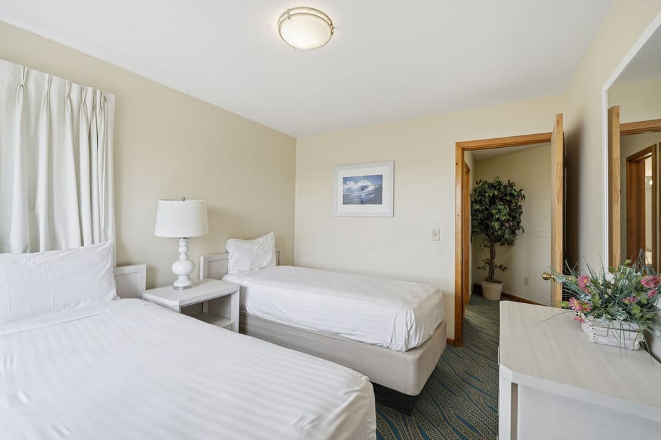 Natural light floods this cheerful room, featuring stylish decor and comfortable twin beds, ideal for a relaxing beach getaway.