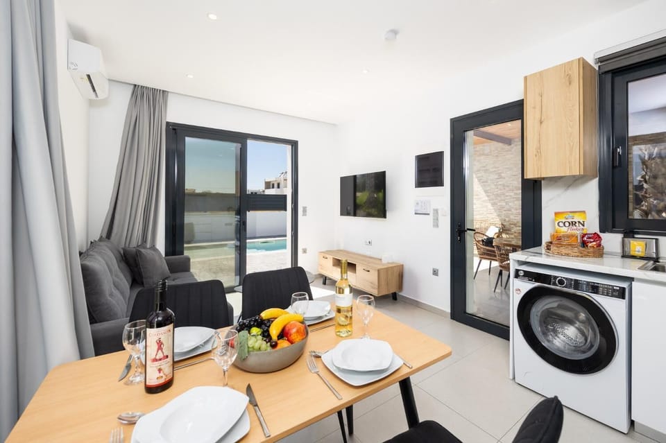 Open-plan living room with sofa, dining area, kitchen, A/C, WiFi internet, and satellite TV