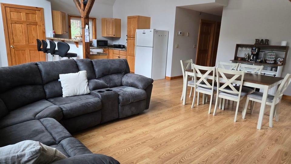 Open-concept kitchen, dining table, and sectional sofa inside modern cabin.
