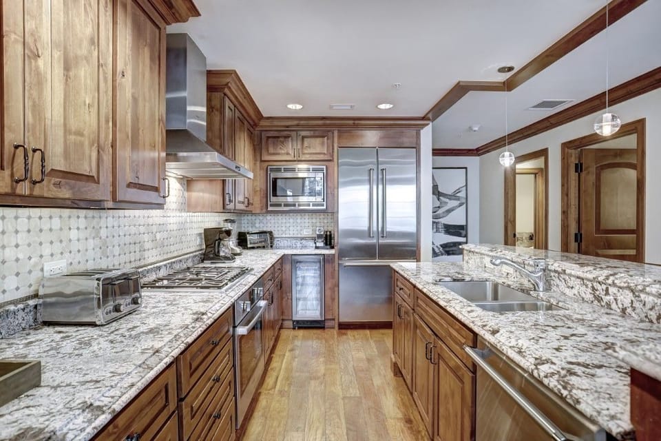 Modern kitchen equipped with high-end appliances, beautiful granite countertops, and rich wooden cabinetry, perfect for culinary endeavors.