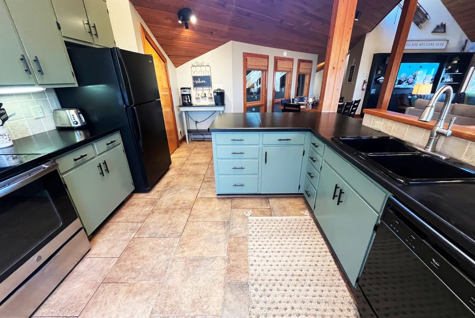 Kitchen has Electric Stainless Steel Stove and Oven, Microwave, Dishwasher, Refrigerator, Double Sink, and is stocked with some essentials such as spices and coffee pods