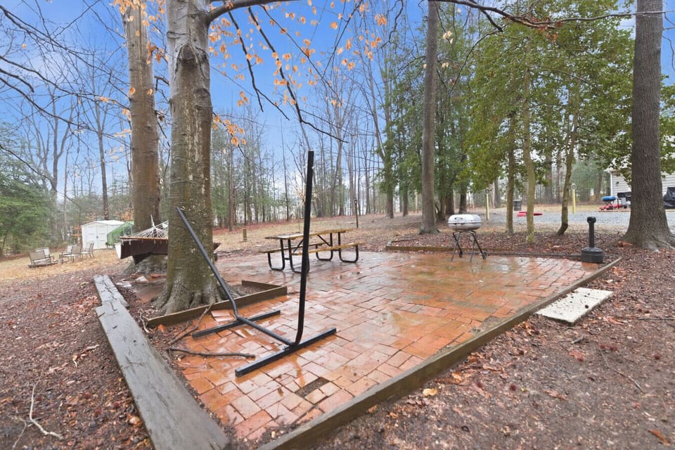 Relax on the brick patio surrounded by trees, complete with two hammocks, a picnic table for outdoor meals, cornhole boards, and a smoker’s pole for guest use. A perfect spot to unwind in the fresh air.
