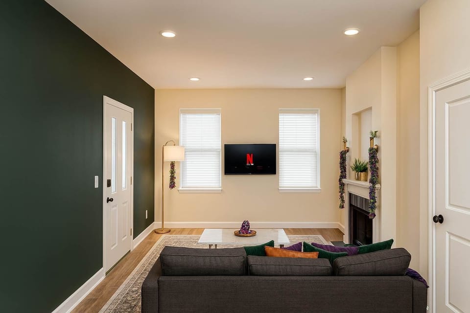 Open living area with recessed lighting, smart TV, and green accent wall just inside the front door.