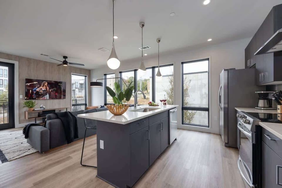 Unit 1: Fully equipped kitchen with stainless steel appliances, basic cooking essentials, toaster, coffee machine, and kitchen island seating.