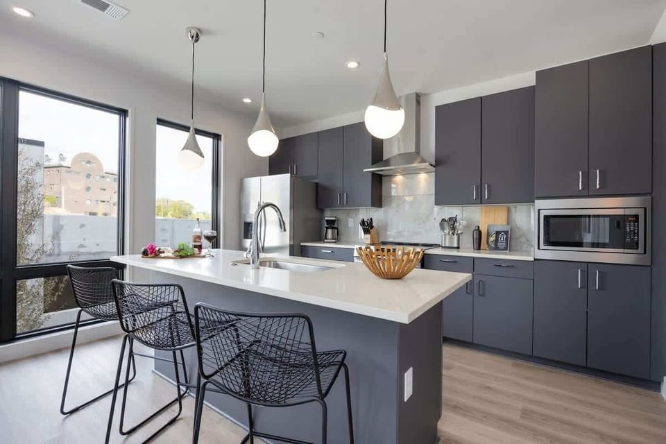 Unit 1: Fully equipped kitchen with stainless steel appliances, basic cooking essentials, toaster, coffee machine, and kitchen island seating.