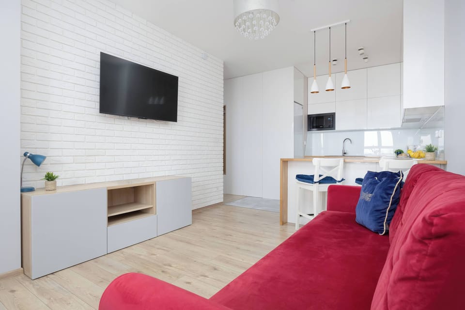 Open living space with a red sofa, dining table and bright windows creating an inviting atmosphere.