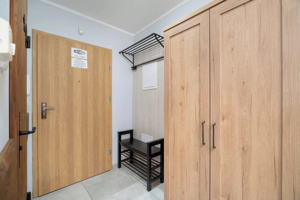 A hallway with a large wooden wardrobe and mirror. The neutral tones give it a neat and tidy appearance.