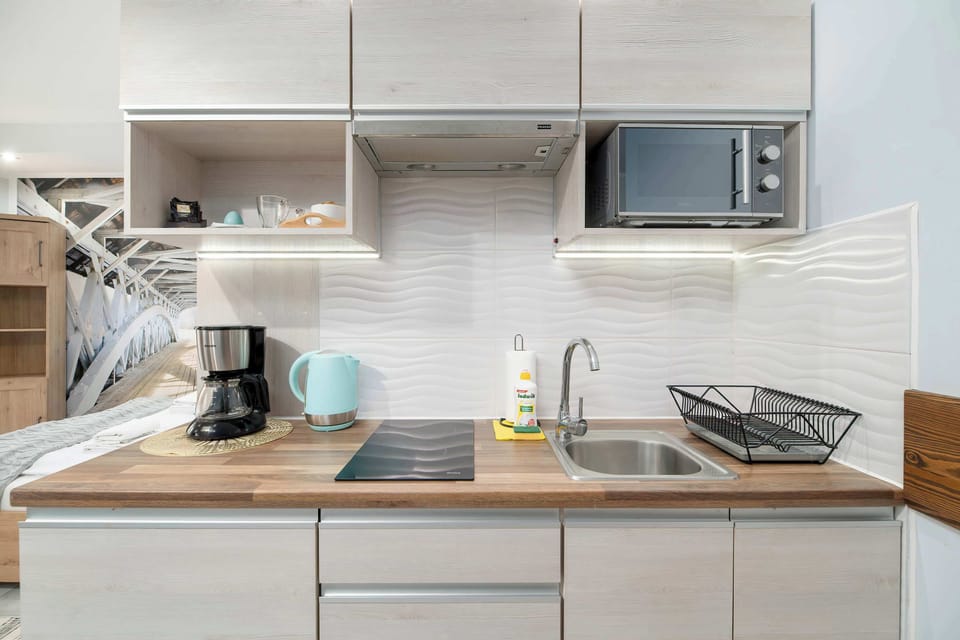 A modern kitchen featuring white cabinets, wooden accents, and a microwave. It looks fully equipped for a comfortable stay.
