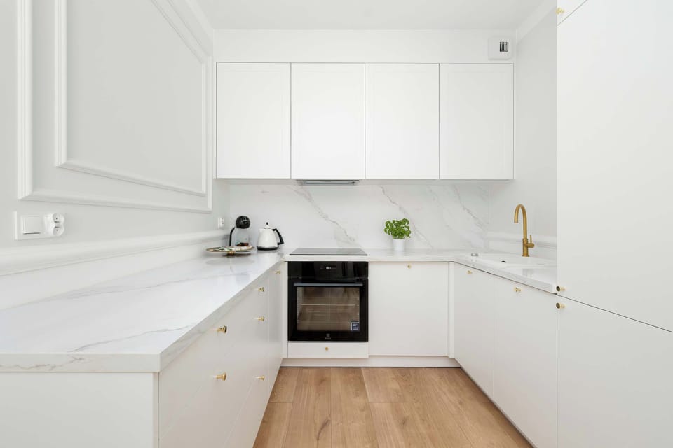 A modern kitchenette with white cabinets and high-quality appliances that allows you to prepare home-cooked meals. 