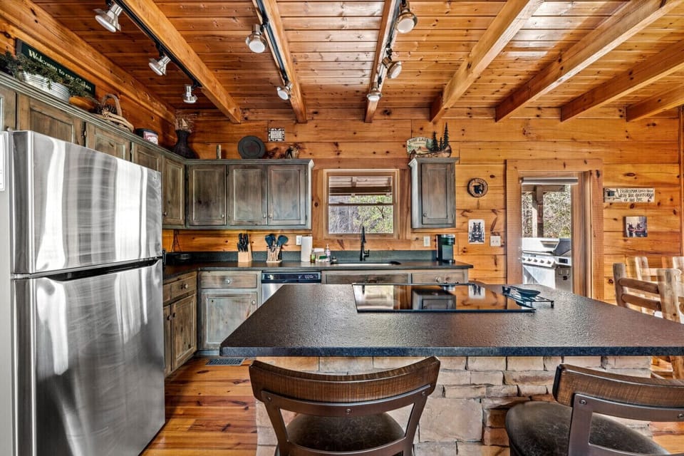 Gather in this warm, wood-toned kitchen with stone-accented island, sleek cooktop, and cozy views that bring the Smokies right to your breakfast bar.
