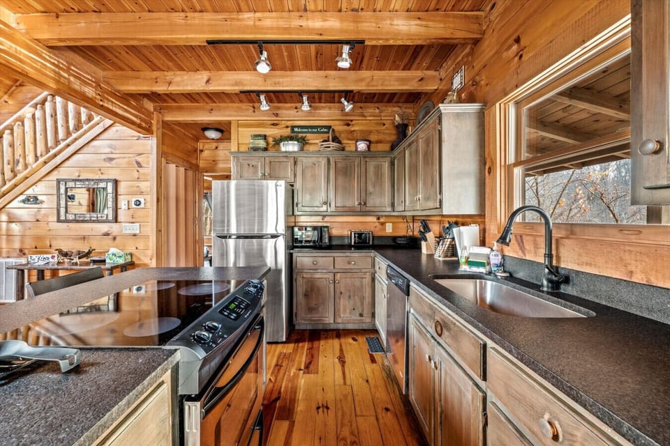 Make meals with ease in this inviting kitchen featuring stainless steel appliances, rustic cabinetry, and a big window that brings the outdoors in.